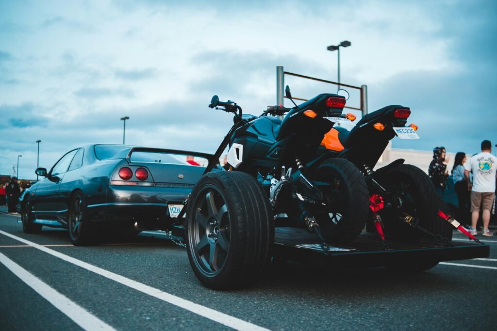 A sleek car followed by two motorcycles parked outdoors in an urban setting.